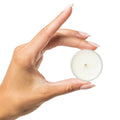Round white candle held between hands