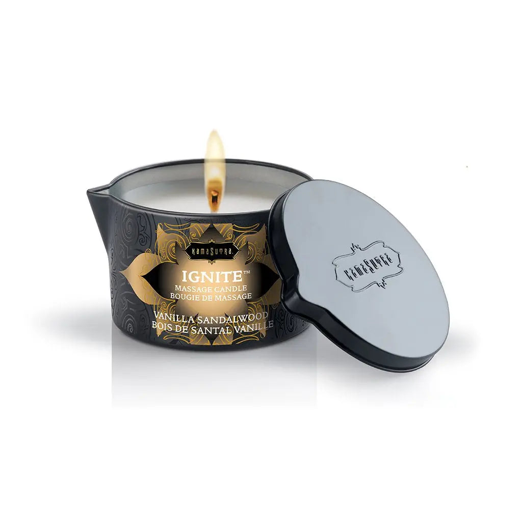 Massage candle with vanilla sandalwood label, dark tin, lid off, flame burning